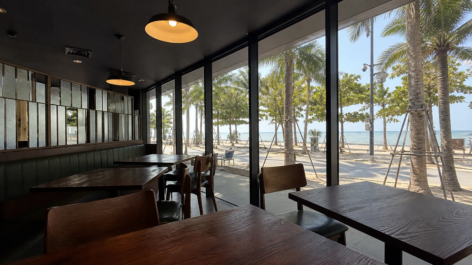 大きな窓の向こうにヤシの木と海が見えるカフェの店内